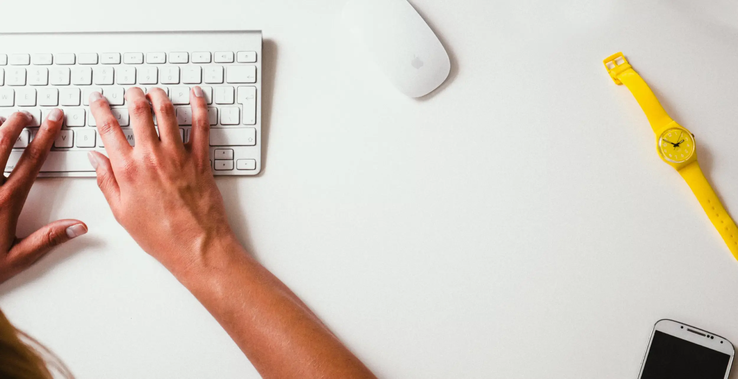 Imagen donde se muestra unas manos encima de un teclado y otros elementos en la mesa